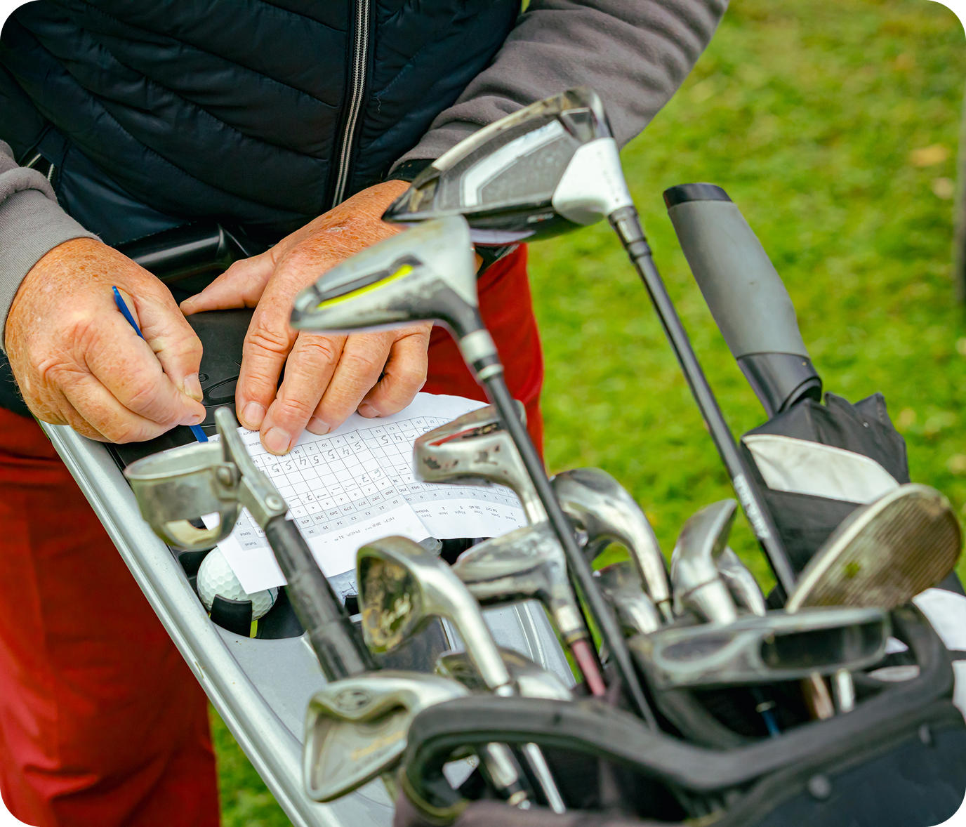 Close-up of golfer with scorecard and clubs