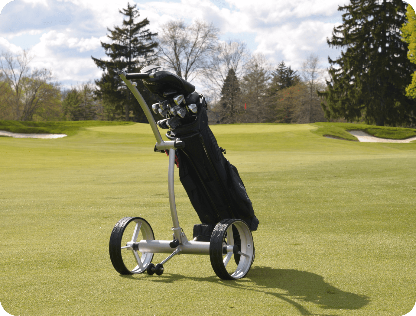 Golf cart with clubs on grassy course.